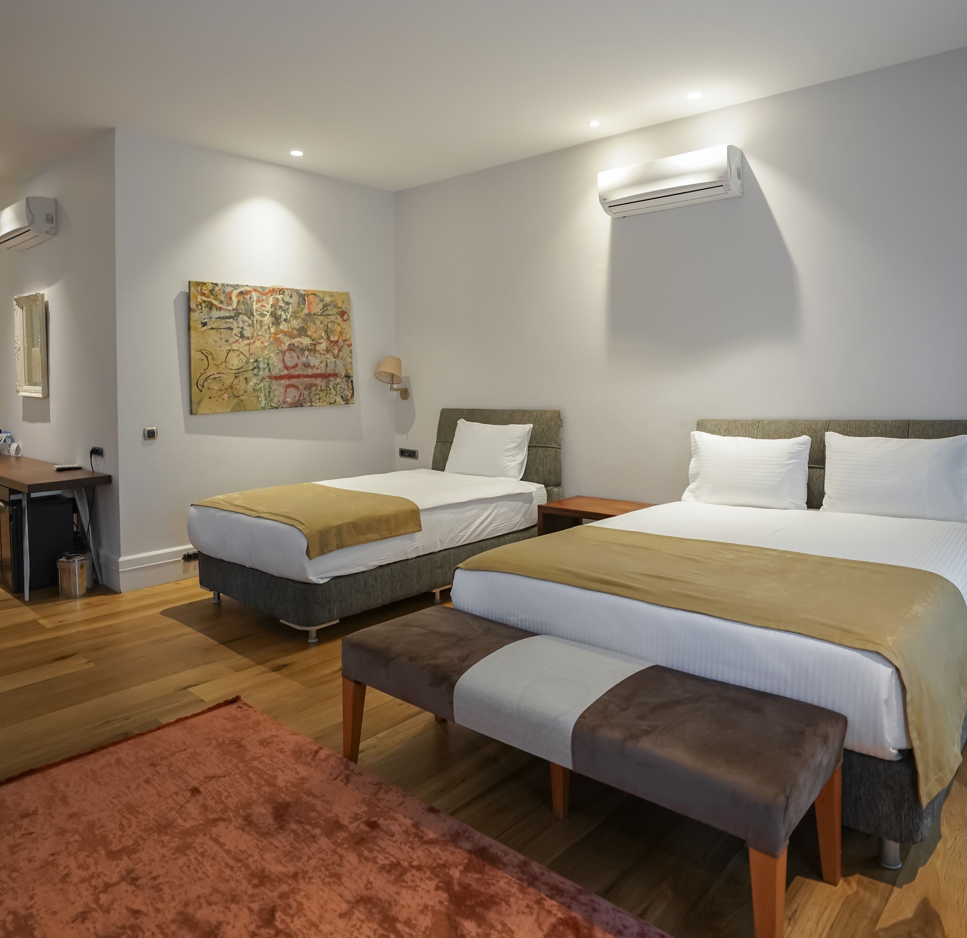 Een hotelkamer met twee bedden, een bureau en een schilderij aan de muur.
