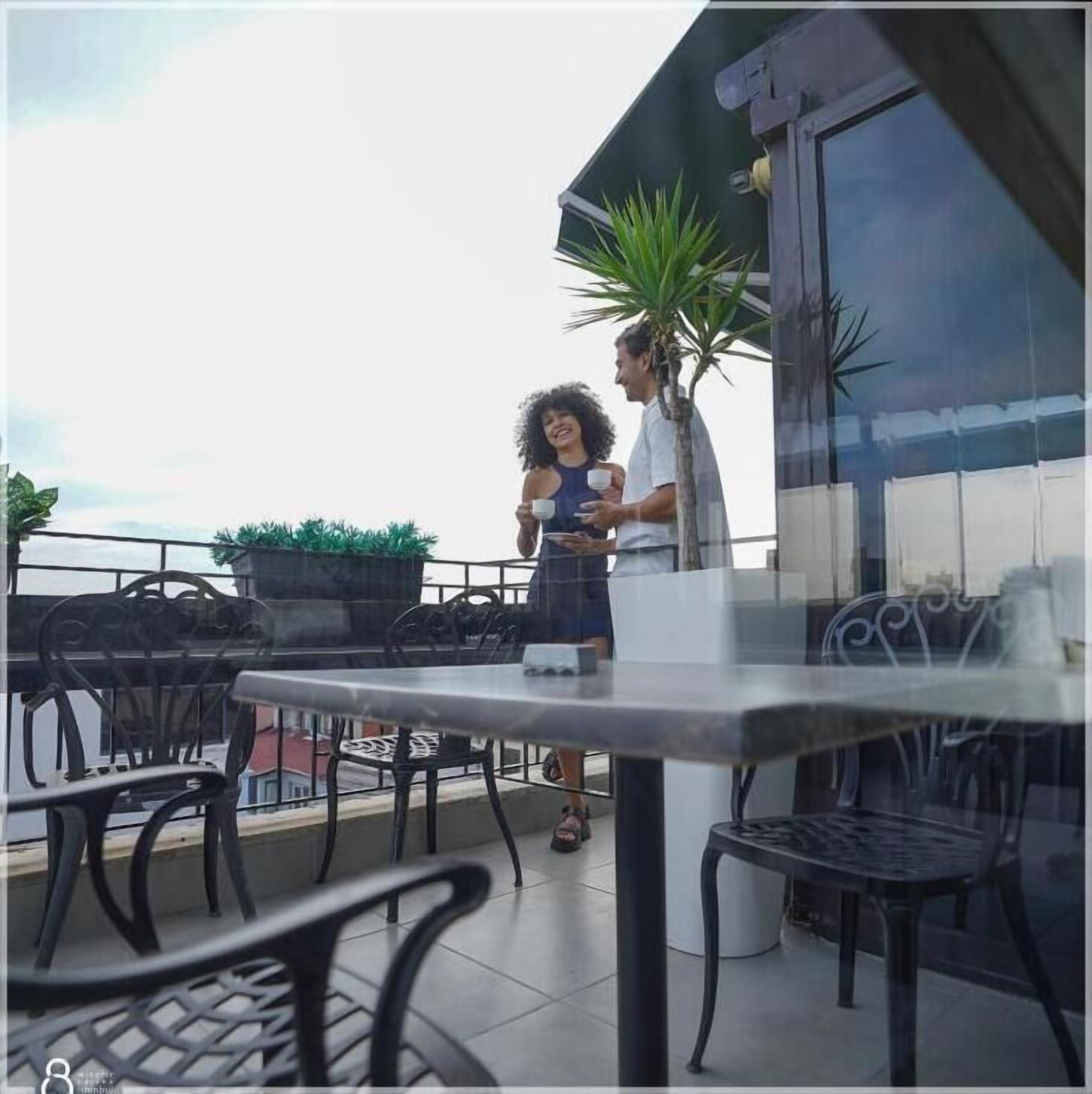 A balcony with outdoor seating, a table, and a potted plant.