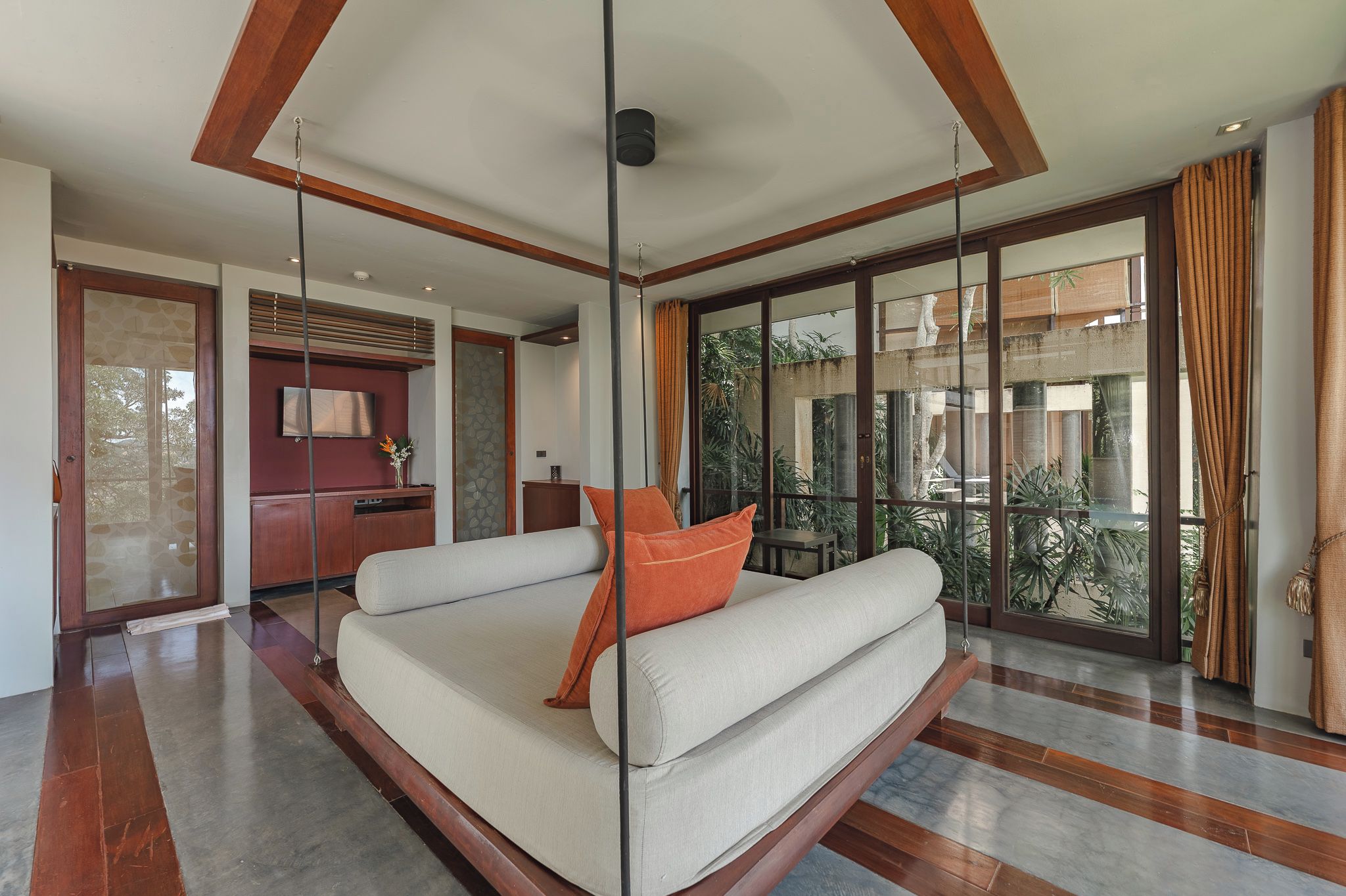 A modern living room with a sofa, a television, and a large glass door leading to a balcony.