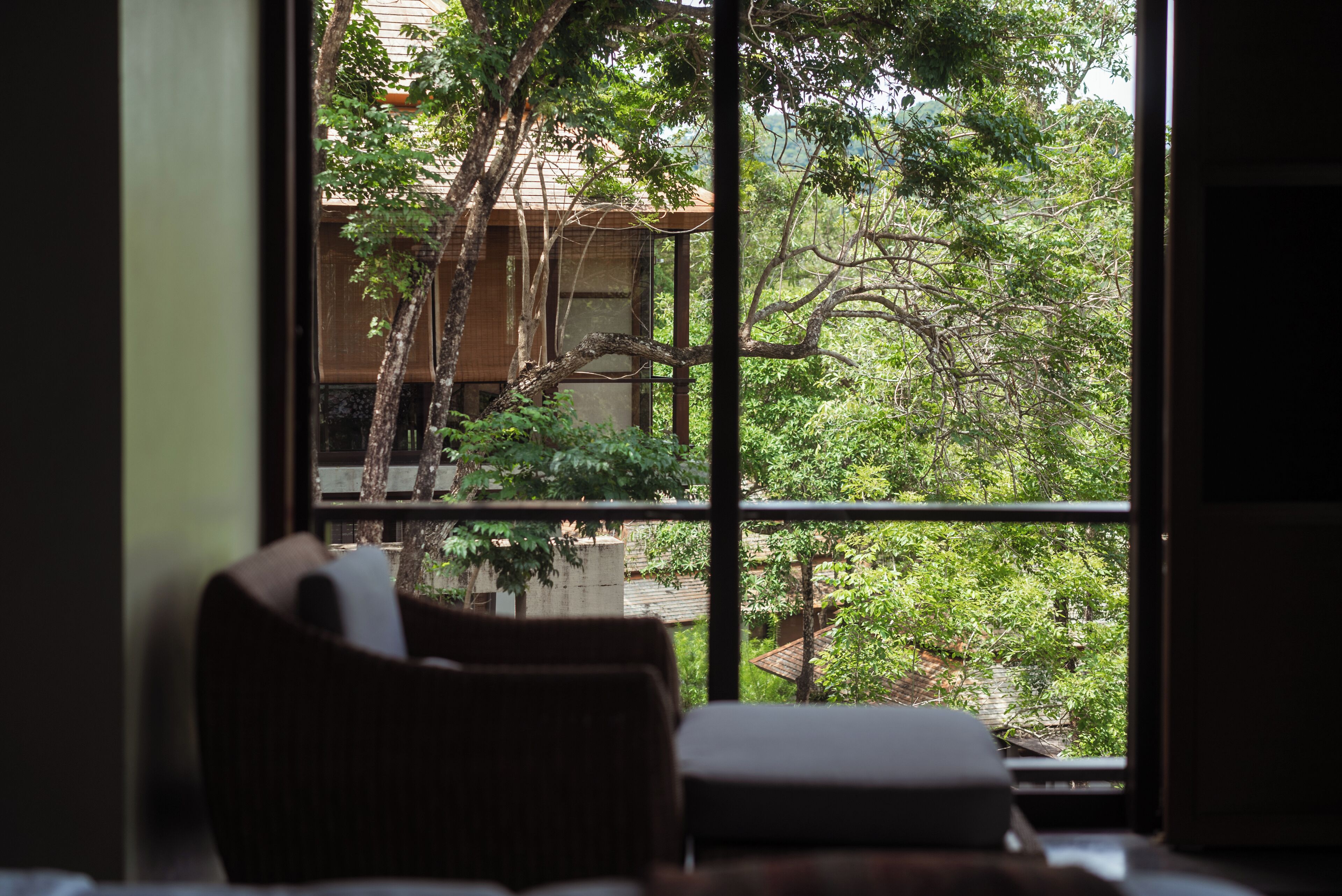 A room with a large window overlooking a lush garden and a building.