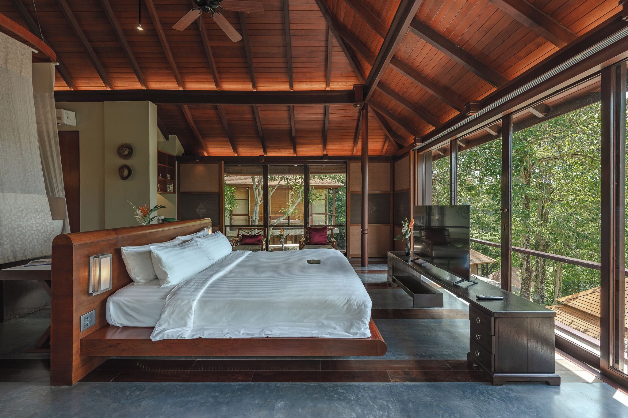 A spacious bedroom with a large bed, a TV, and a view of the outdoors.