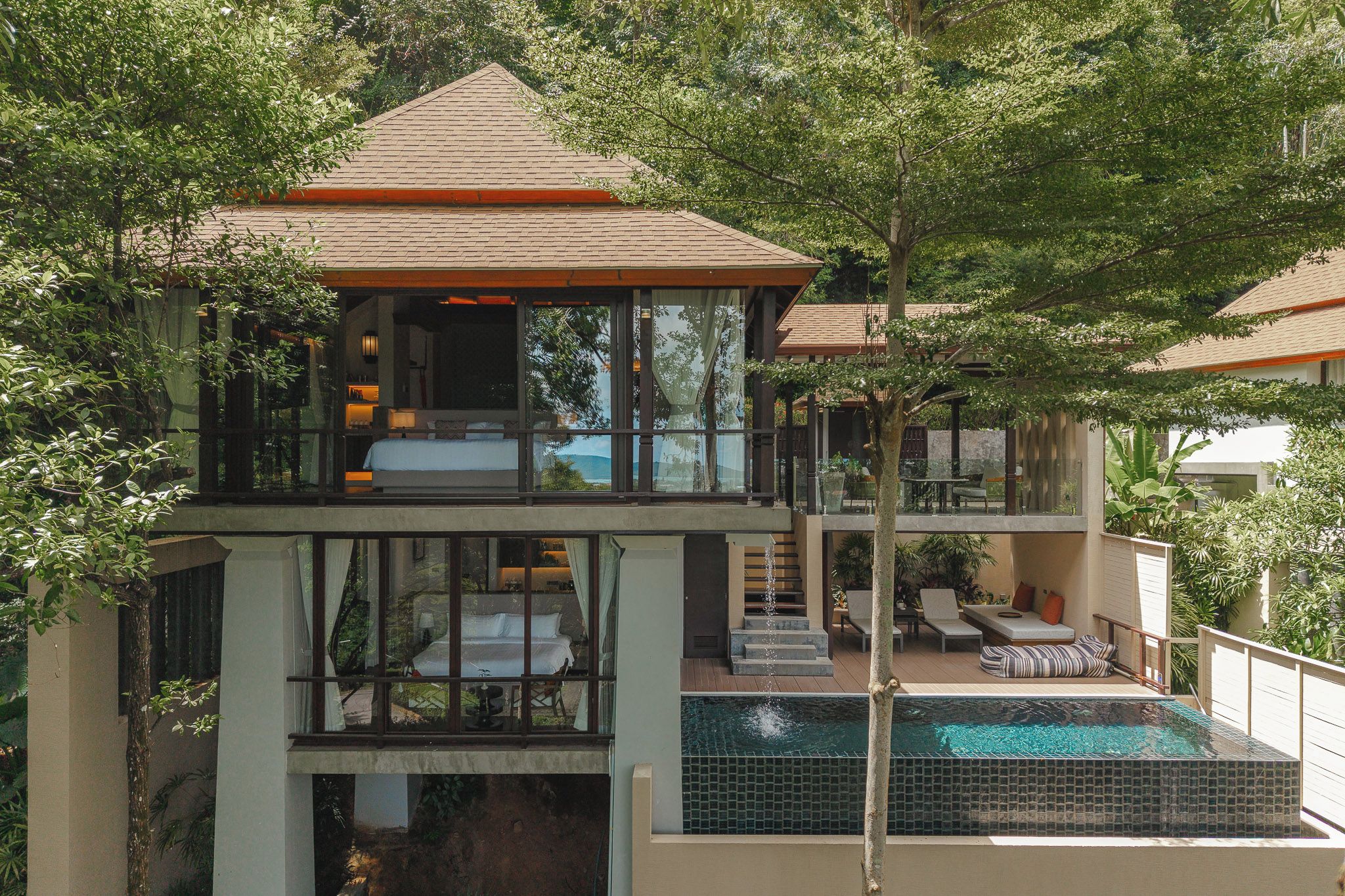 A multi-level house with a swimming pool, balconies, and outdoor seating areas.
