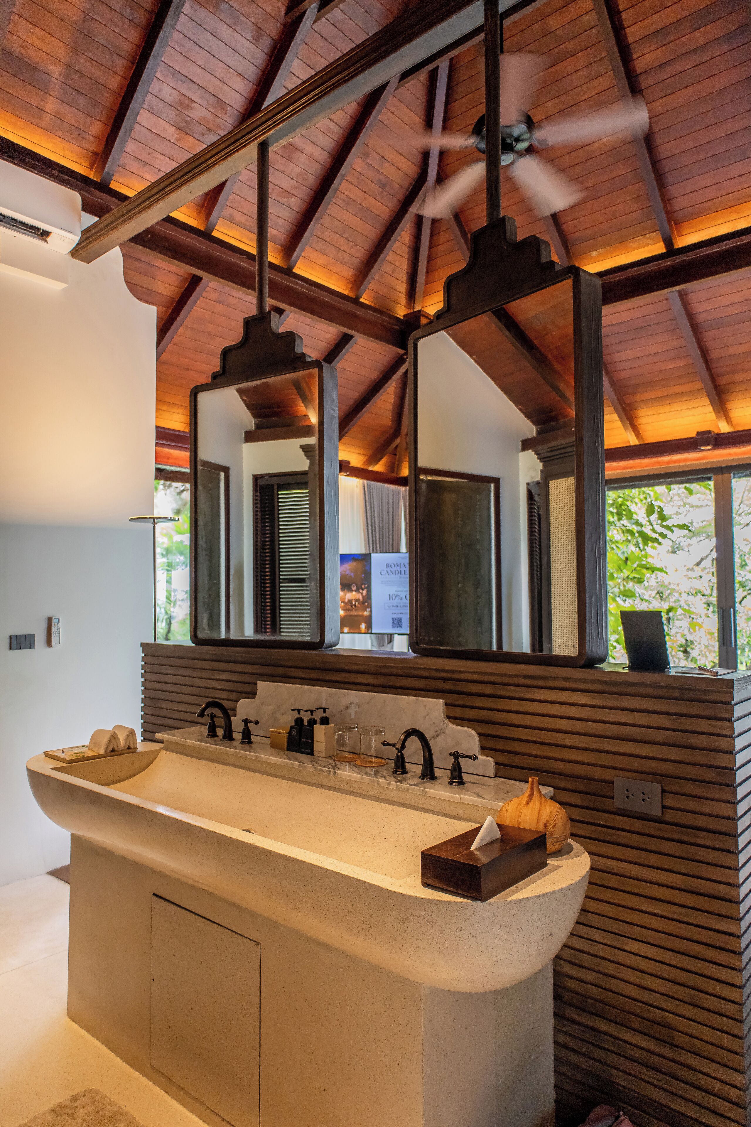 A modern bathroom with a large freestanding sink, two mirrors, and a ceiling fan.