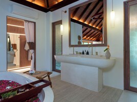 Un baño moderno con un lavamanos independiente, un espejo grande y un techo de madera.