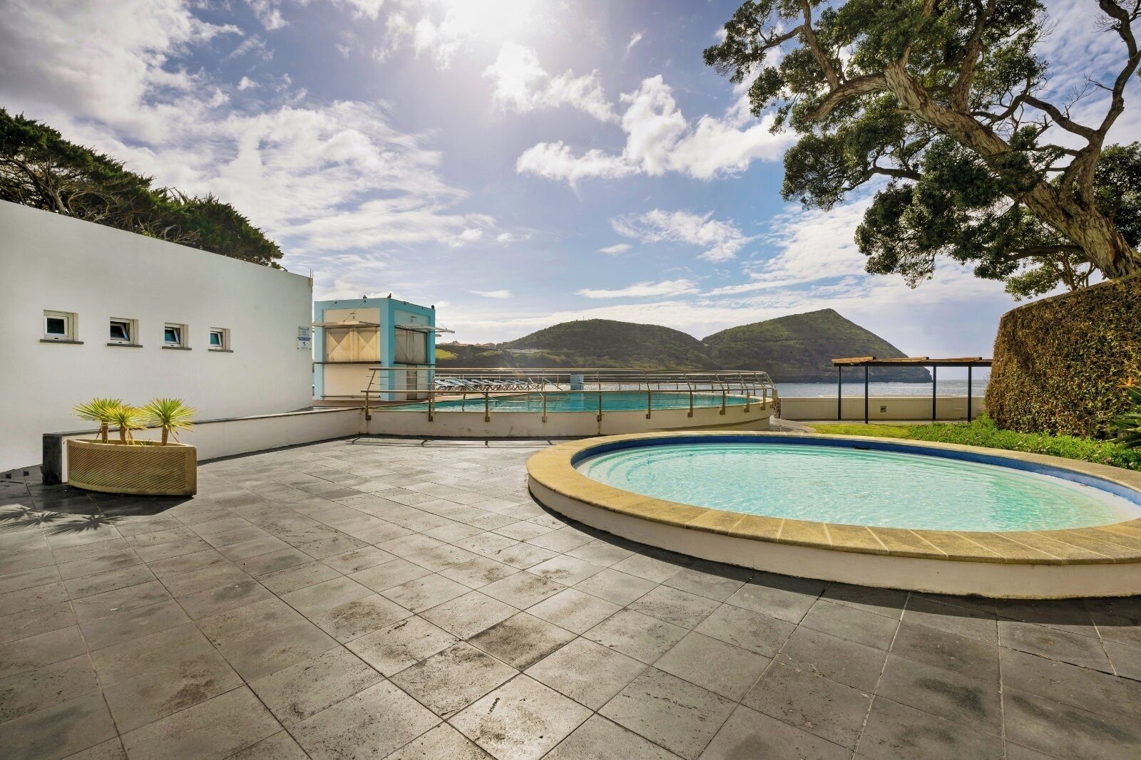 A rooftop pool area with a view of the sea and hills.