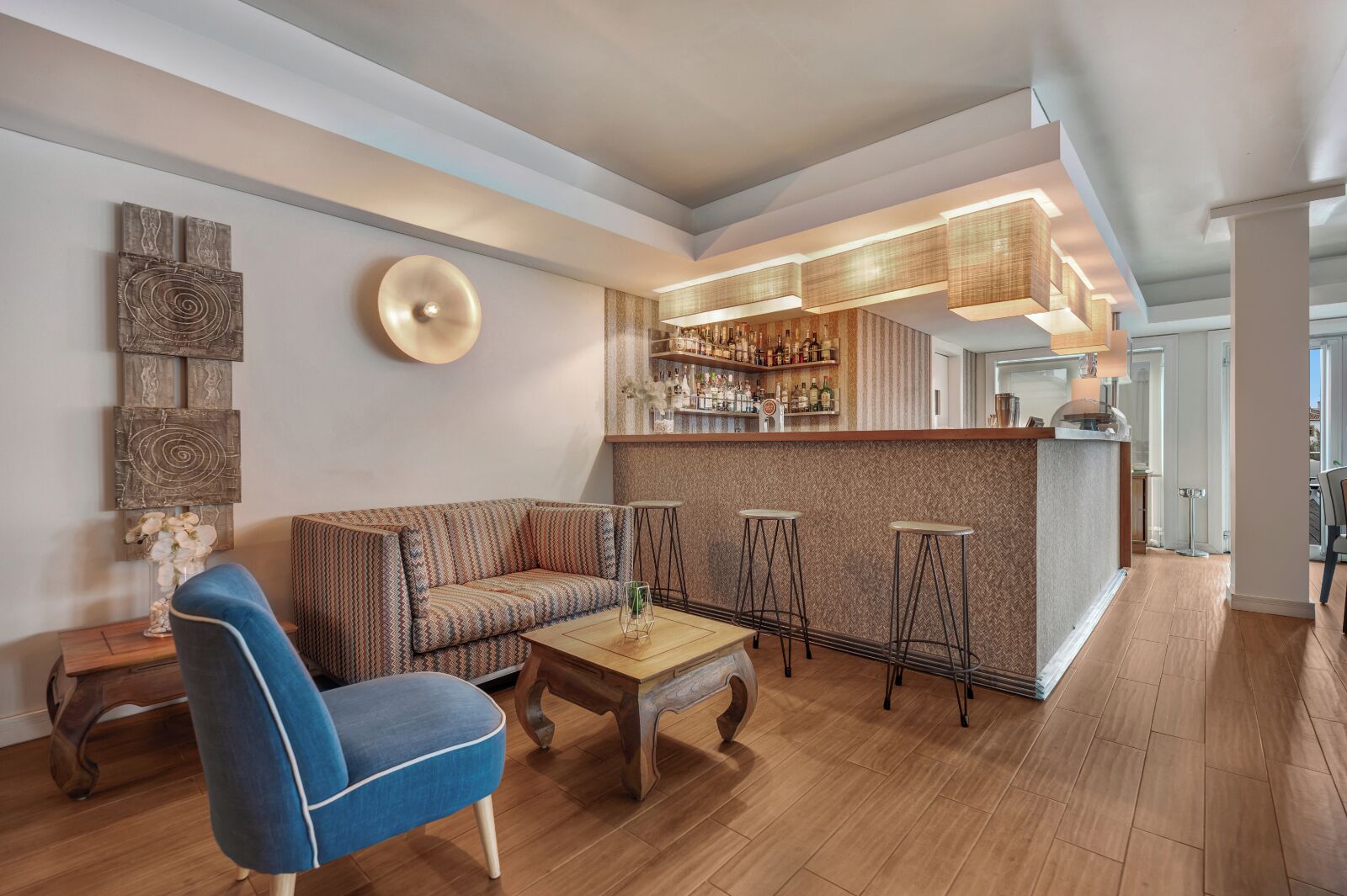 A modern living area with a sofa, a coffee table, and a bar area with stools.
