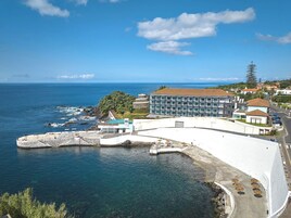 Un hotel costero con un edificio amplio, piscina y vistas al mar.