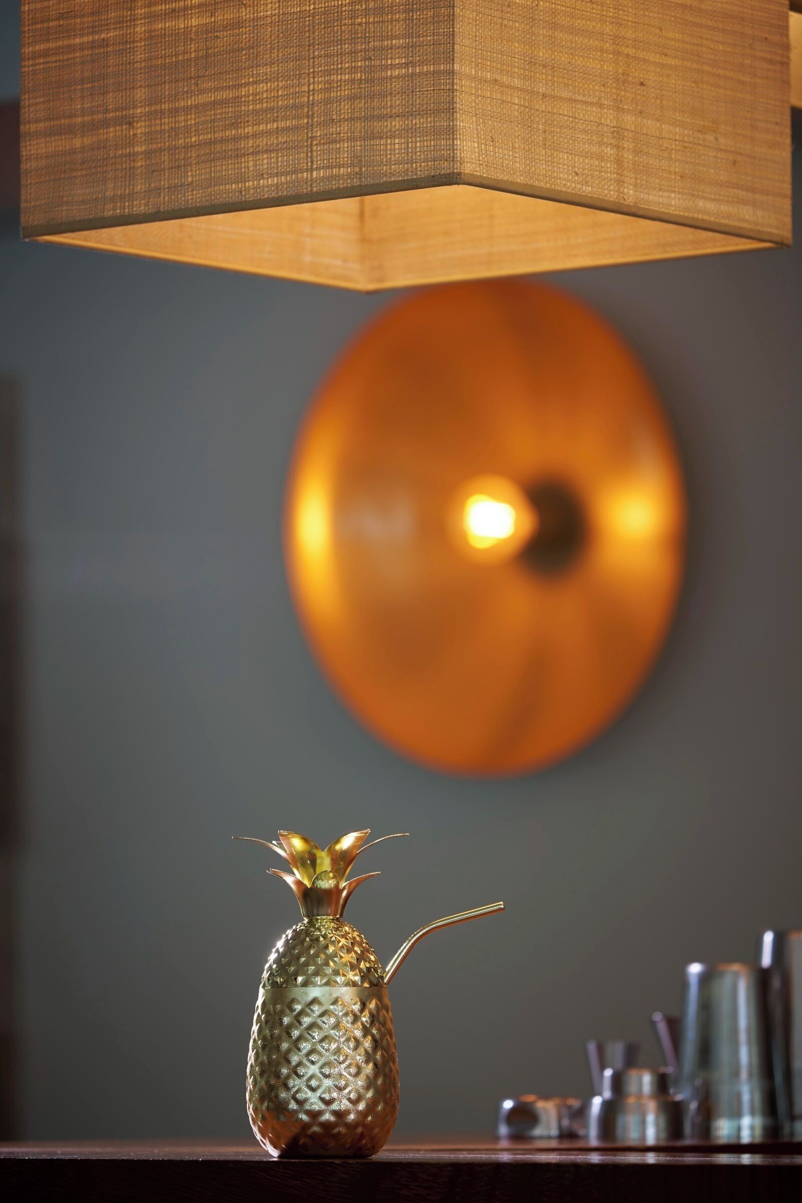 Un florero con forma de piña y una pajita sobre una superficie de madera.