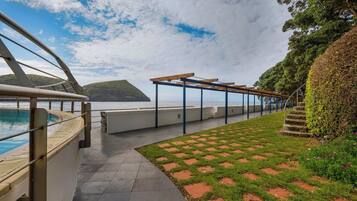 A covered outdoor area with a pool, a pergola, and a view of the sea.
