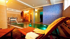 Uma área de piscina com espreguiçadeiras de madeira, um toboágua e uma parede de mosaico azul.