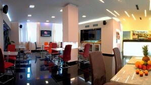 Um saguão de hotel com área de bar, assentos e uma televisão.