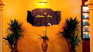 Um hall de entrada com um candelabro, uma placa com a inscrição 'Relax Inn' e duas plantas em vasos.