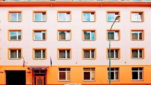 A multi-story hotel with a uniform facade, multiple windows, and a ground-level entrance with a sign.