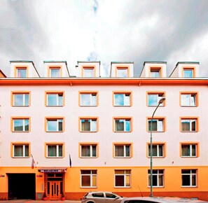 A multi-story hotel with a uniform facade, multiple windows, and a ground-level entrance with a sign.