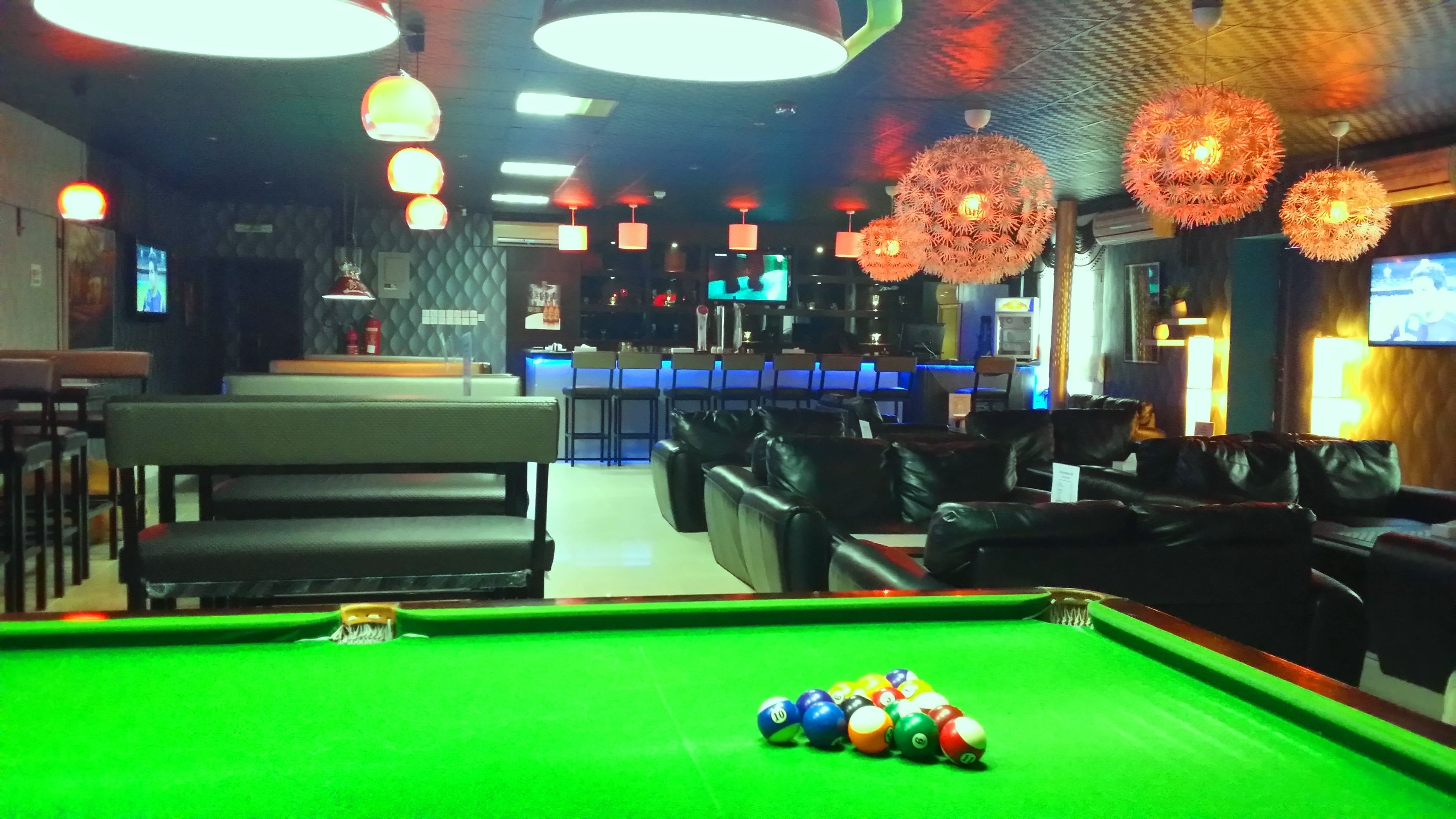 Een biljarttafel met ballen, een pooltafel, en zithoeken met banken en stoelen.