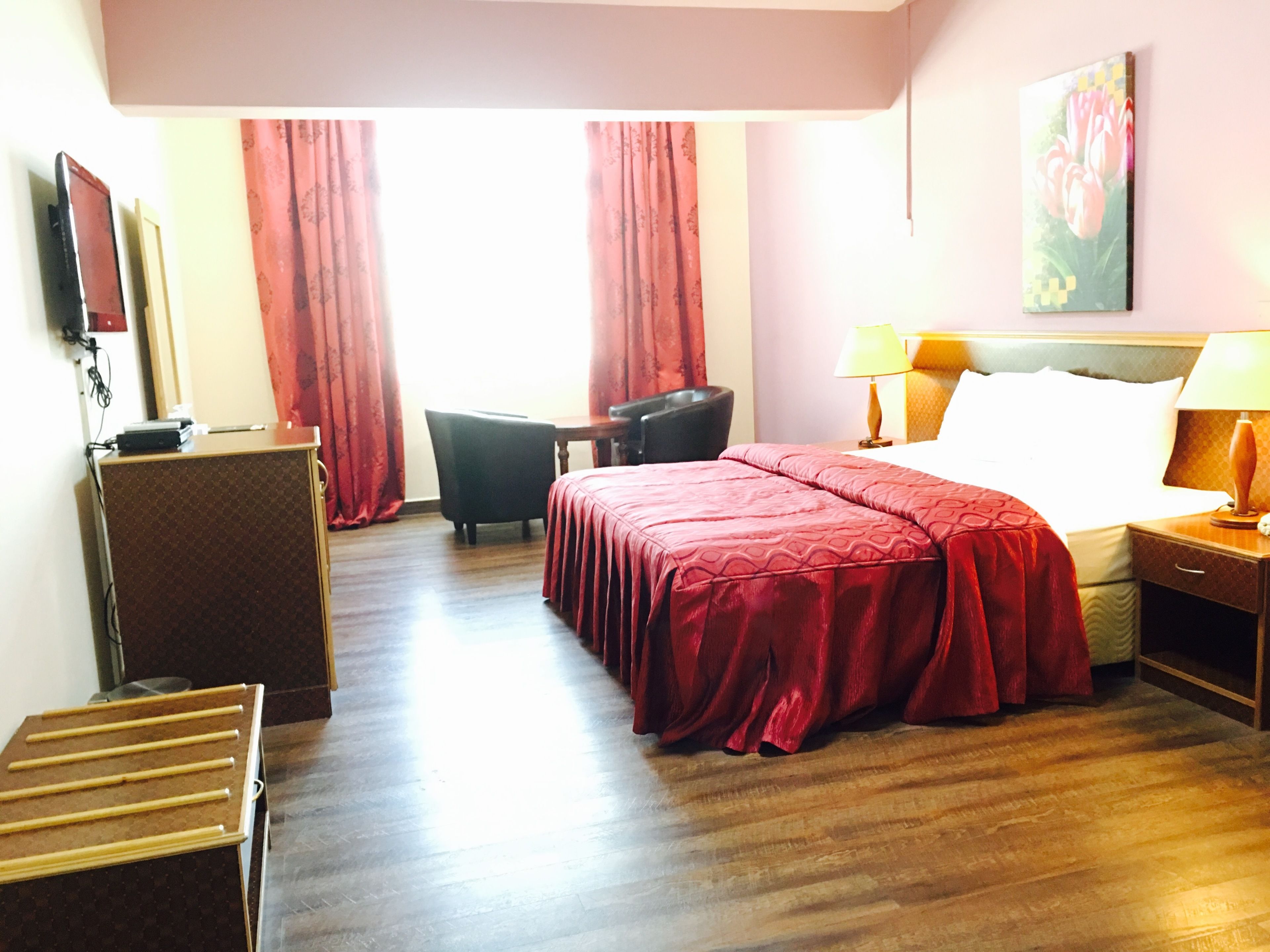 Una habitación de hotel con cama, escritorio, silla, televisor y un cuadro en la pared.