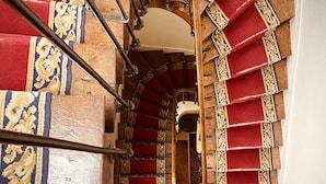 A spiral staircase with red steps and wooden railings. - Logis Hôtel Le Plantagenêt (Chinon)