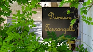 A sign with the text "Demeure Tourangelle" in gold lettering on a black background, surrounded by green foliage. - Logis Hôtel Le Plantagenêt (Chinon)