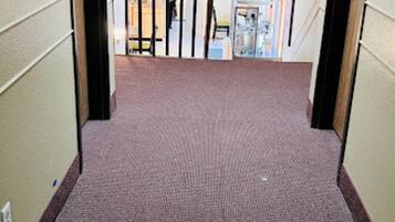 A carpeted hallway with an exit sign above a door.