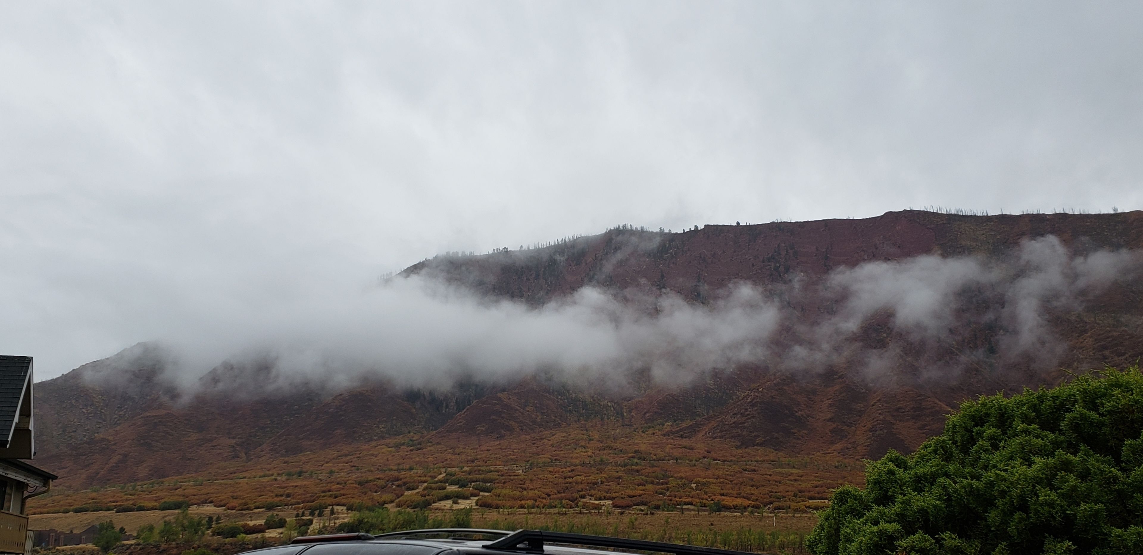 A mountainous landscape with a building in the foreground.