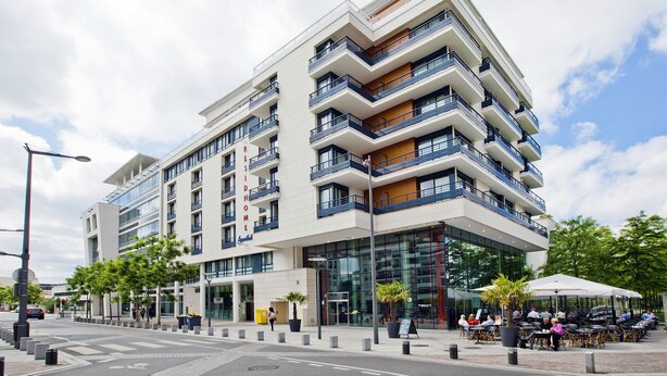 A multi-story hotel with balconies, a glass facade, and outdoor seating areas. - Residhome Monceau (Bois-Colombes)