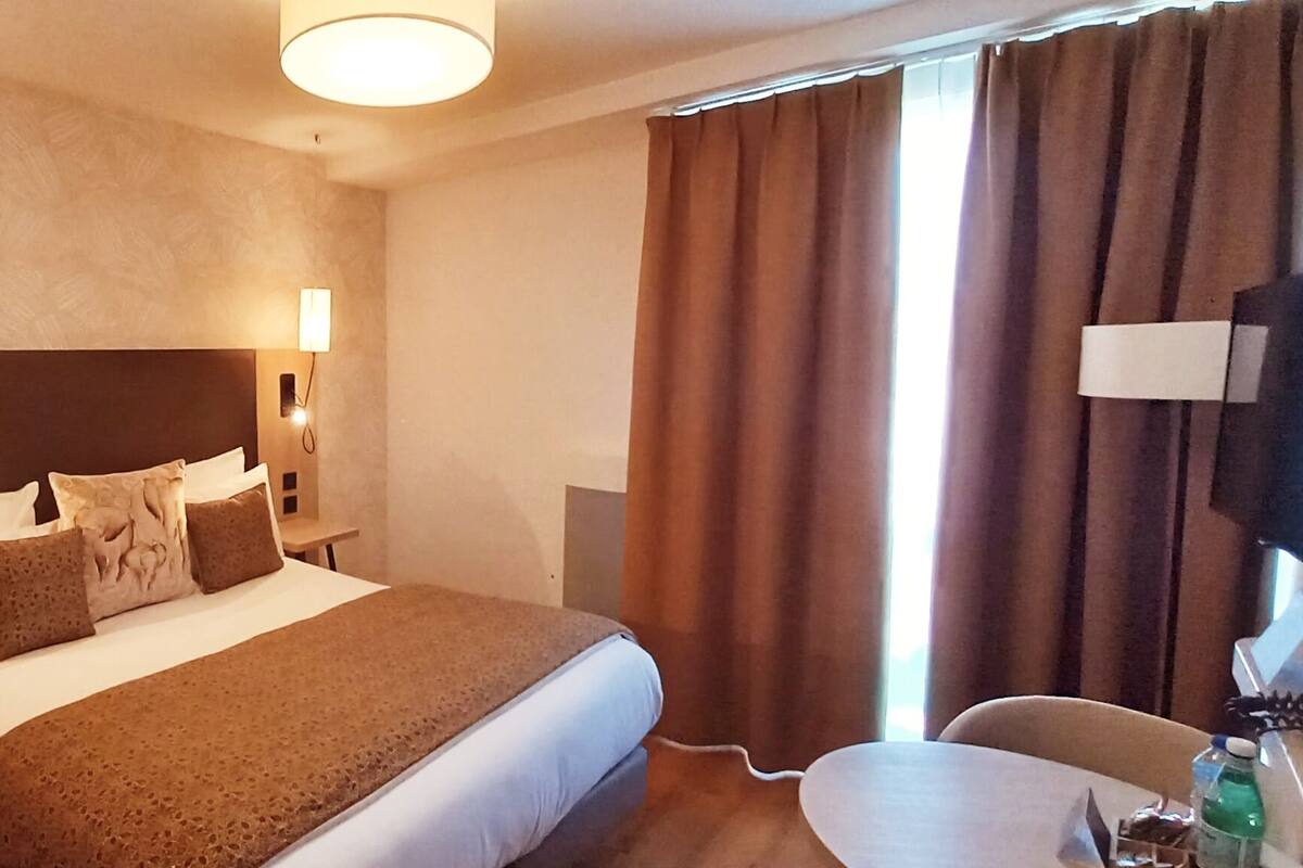 Une chambre d’hôtel avec un grand lit, deux lampes de chevet, une petite table et un téléviseur.