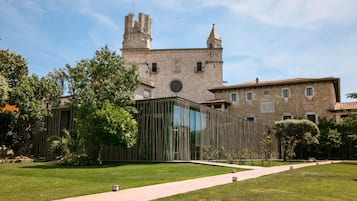 A historic building with a modern glass extension, surrounded by a well-maintained lawn and a paved walkway.