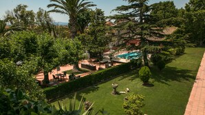 A well-maintained garden with a swimming pool, outdoor seating, and a variety of trees and shrubs.