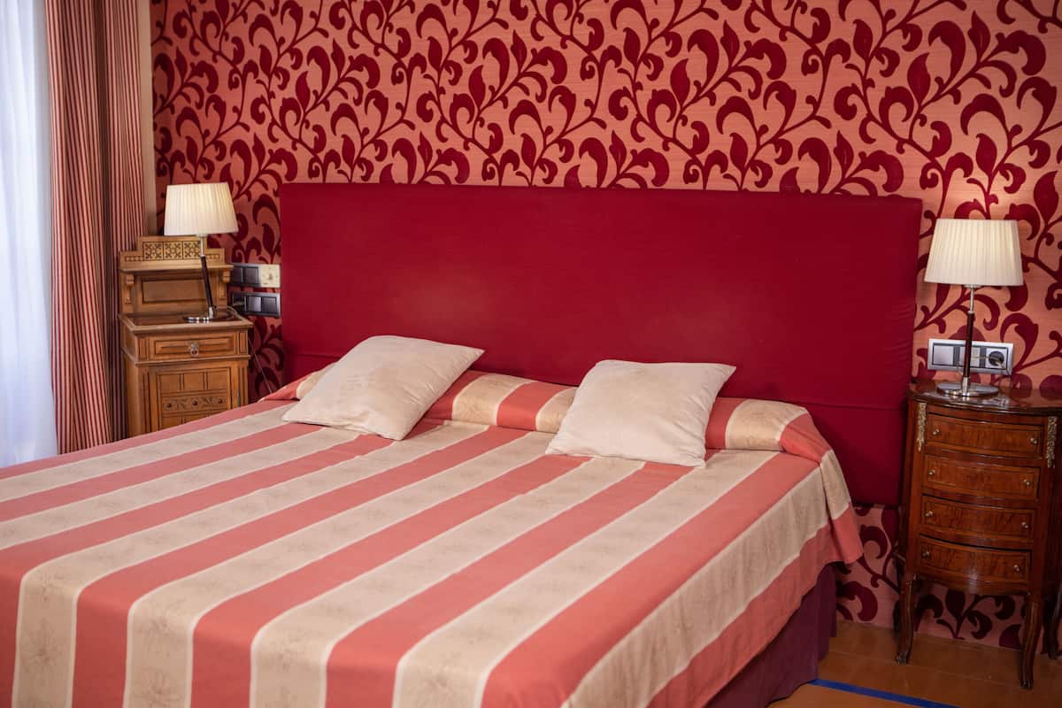 A bed with a striped bedspread, two bedside tables with lamps, and a wooden nightstand.