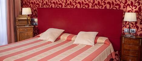 A bed with a striped bedspread, two bedside tables with lamps, and a wooden nightstand.