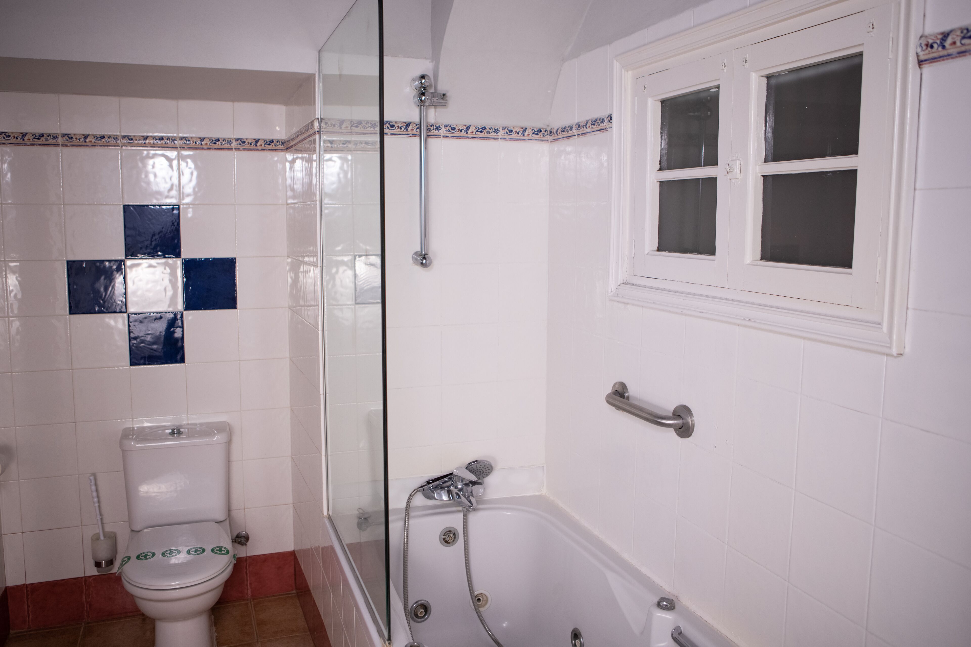 A bathroom with a toilet, a glass-enclosed shower area, and a bathtub.