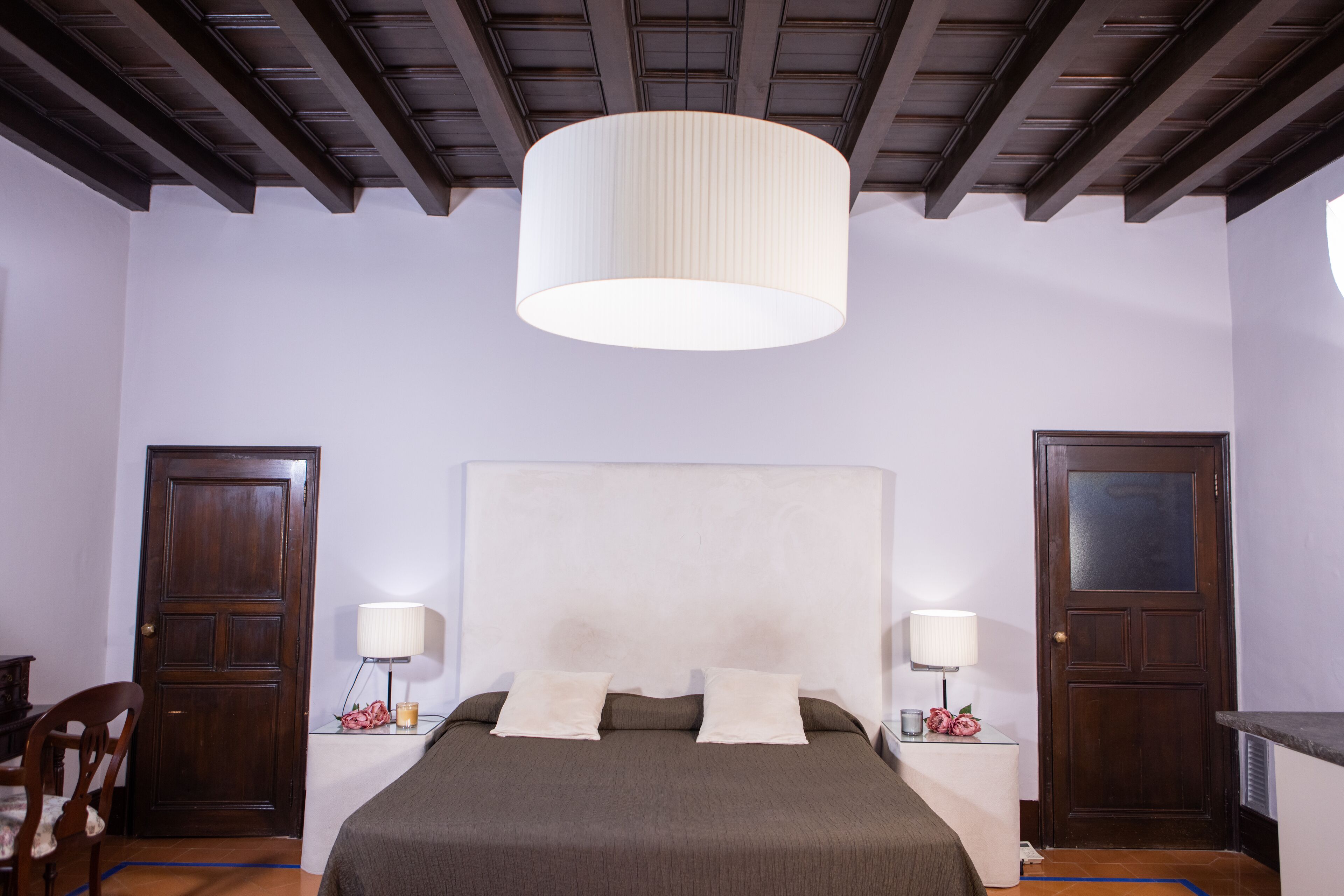 Un dormitorio con una cama grande, puertas de madera y una lámpara en el techo.