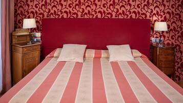 Una habitación de hotel con una cama grande, dos mesitas de noche y un cabecero rojo.
