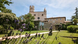 A historic building with a tower, surrounded by well-maintained gardens and a modern glass structure.