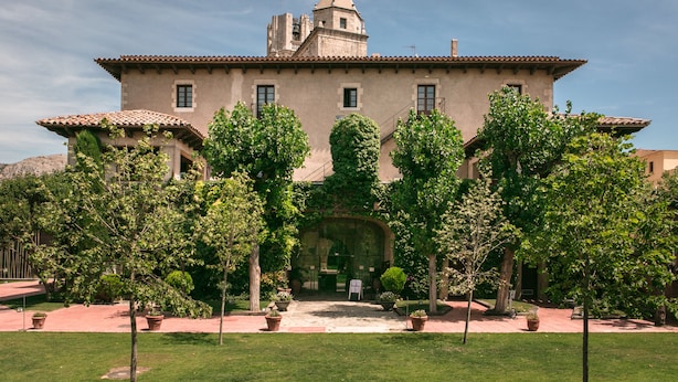 A large building with a central courtyard, surrounded by trees and potted plants.