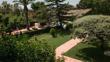 A well-maintained garden with a pathway, various trees, and a pool area.