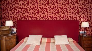 A neatly made bed with striped bedding, two bedside tables with lamps, and a patterned wallpaper.