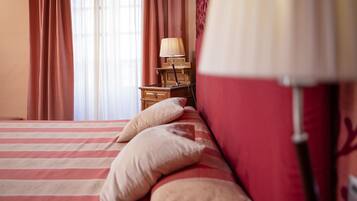 Una cama con ropa de cama a rayas y almohadas, una mesita de noche con lámpara y cortinas.