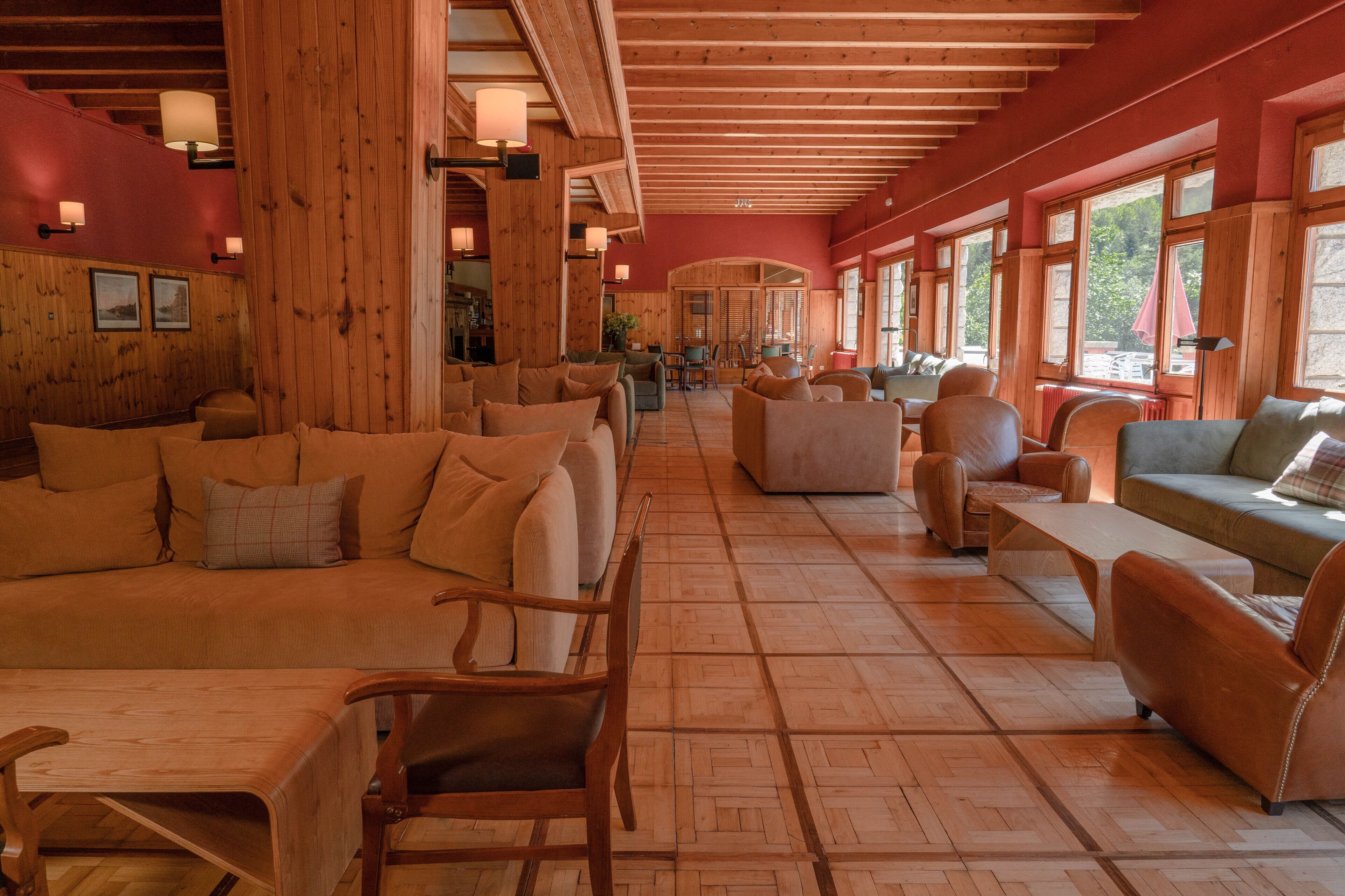 A spacious lobby with wooden flooring, multiple seating areas, and large windows allowing natural light.