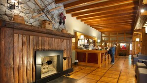 A wooden interior with a stone wall, a fireplace, and a bar area. - Hotel Manantial- Balneari Caldes de Boi (La Vall de Boi)