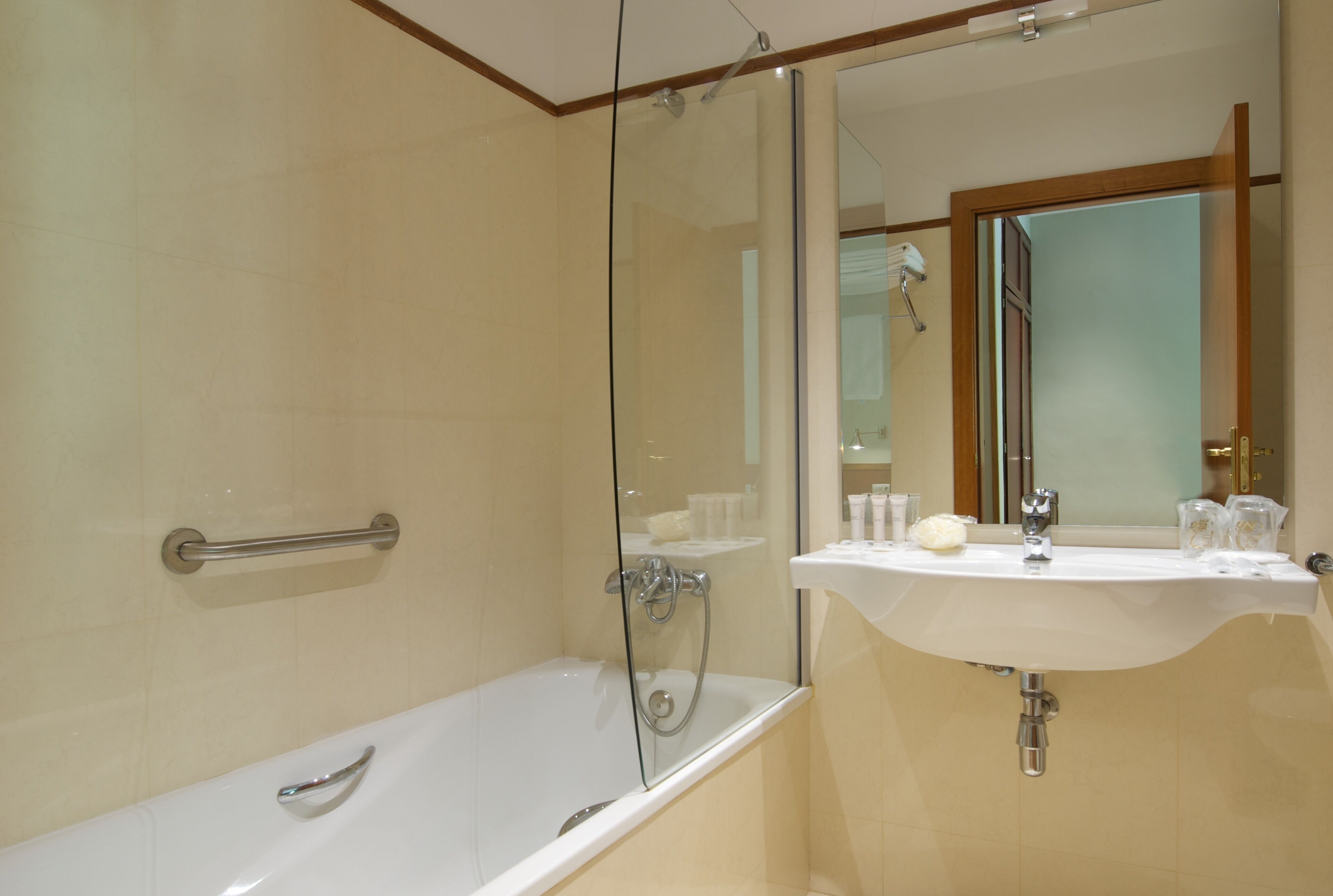 Une salle de bain moderne avec une douche à parois de verre, une baignoire blanche et un lavabo agrémenté d’articles de toilette.