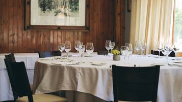 A dining area with a round table set for four, wooden paneled walls, and a framed picture on the wall.