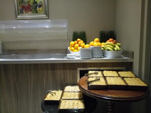 A buffet area with various food items including fruits, vegetables, and desserts.