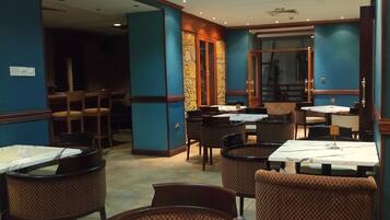 A restaurant interior with blue walls, wooden doors, and tables with white tablecloths.