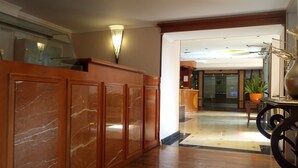 A lobby with a marble reception desk, a potted plant, and a modern interior design.