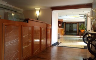 A lobby with a marble reception desk, a potted plant, and a modern interior design.