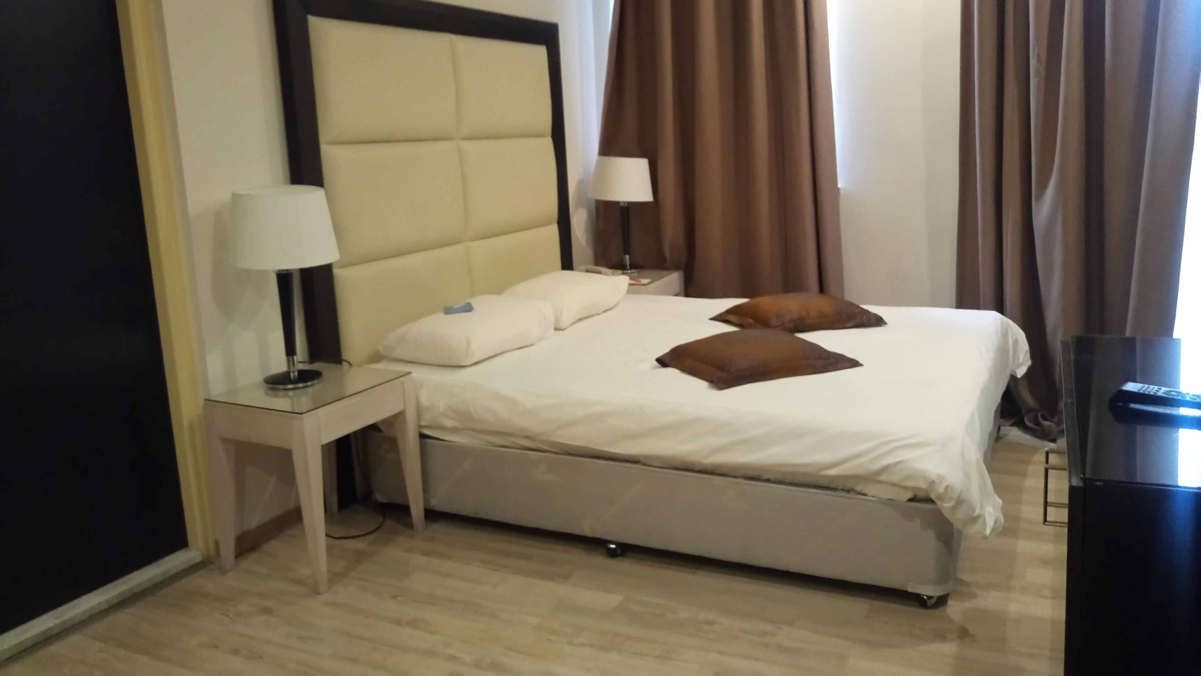 A hotel room with a bed, two bedside lamps, a nightstand, and a TV.