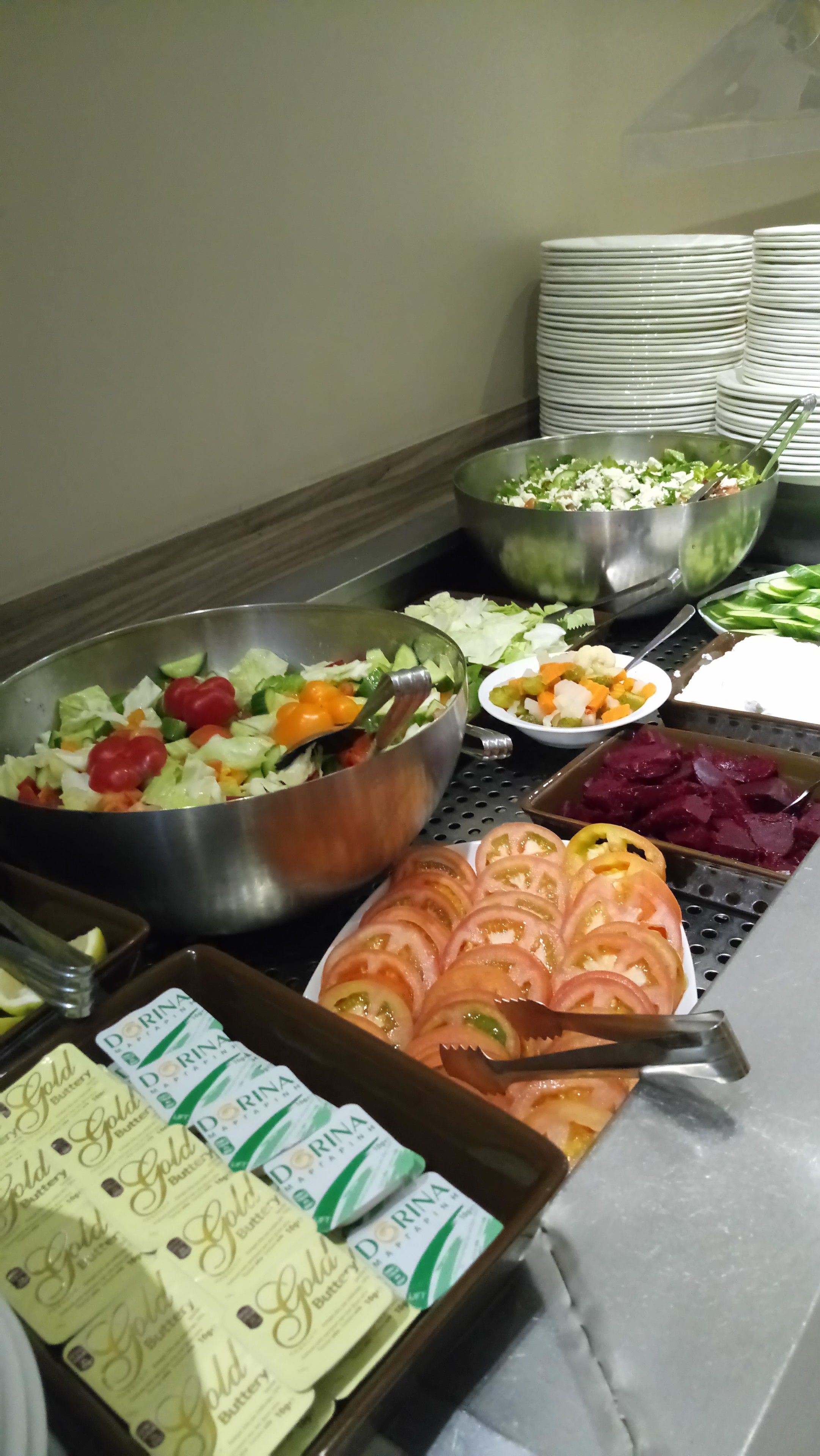 A buffet with various food items including a salad, sliced tomatoes, and Dorina Gold Butter biscuits.