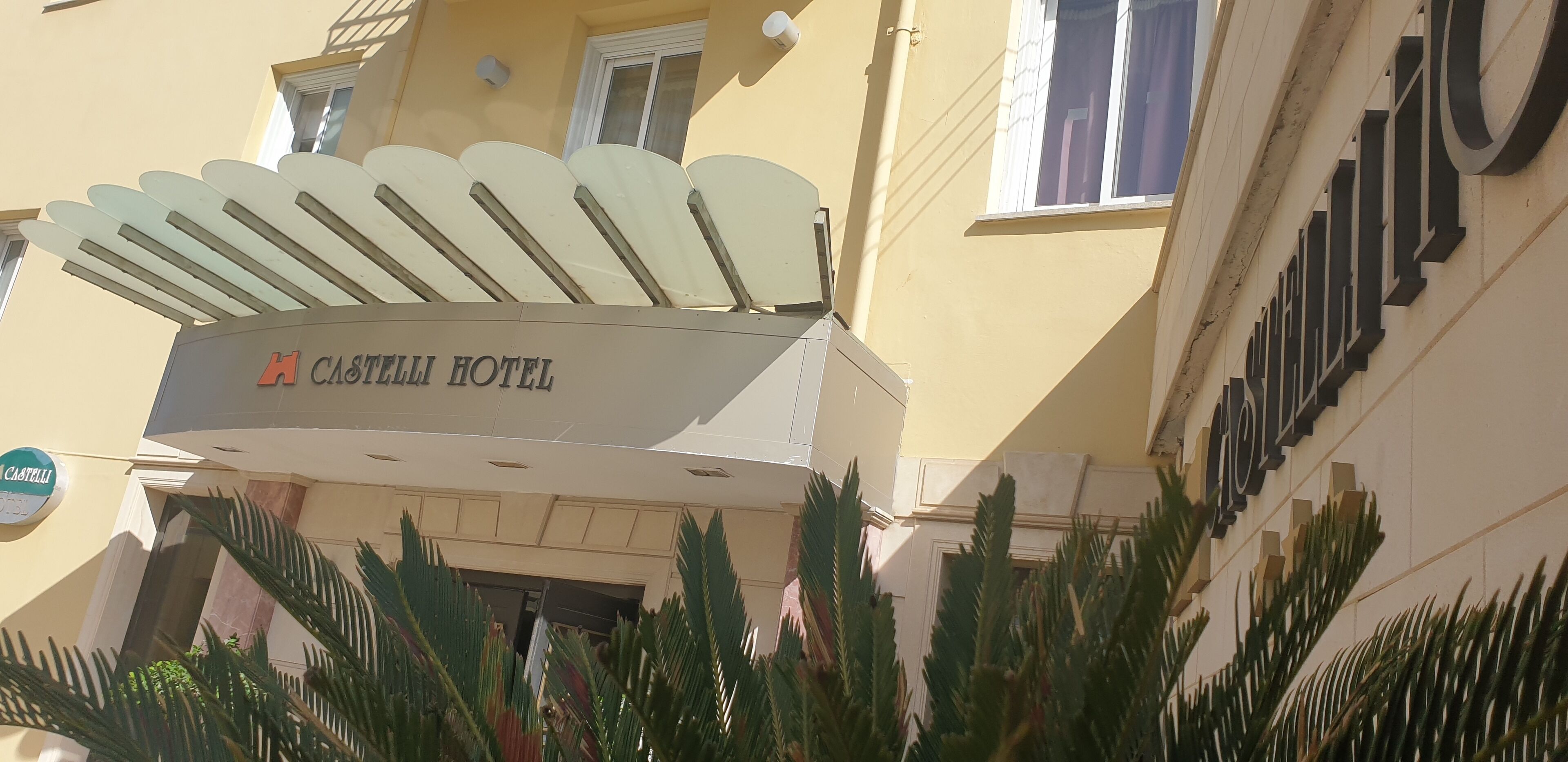 Segnaletica di un hotel con un design originale a forma di ventaglio, con il nome "CASTELLI HOTEL" ben visibile.