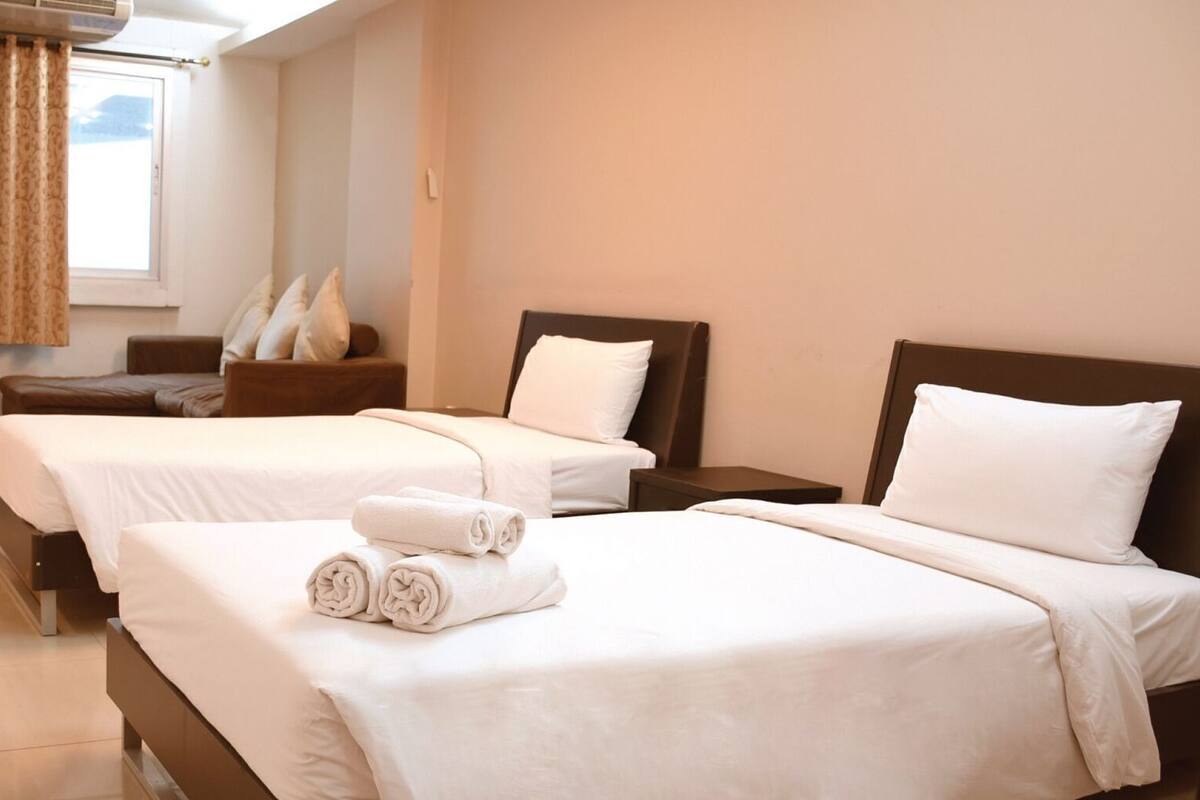 A hotel room with two beds, a desk, a chair, and a window with curtains.